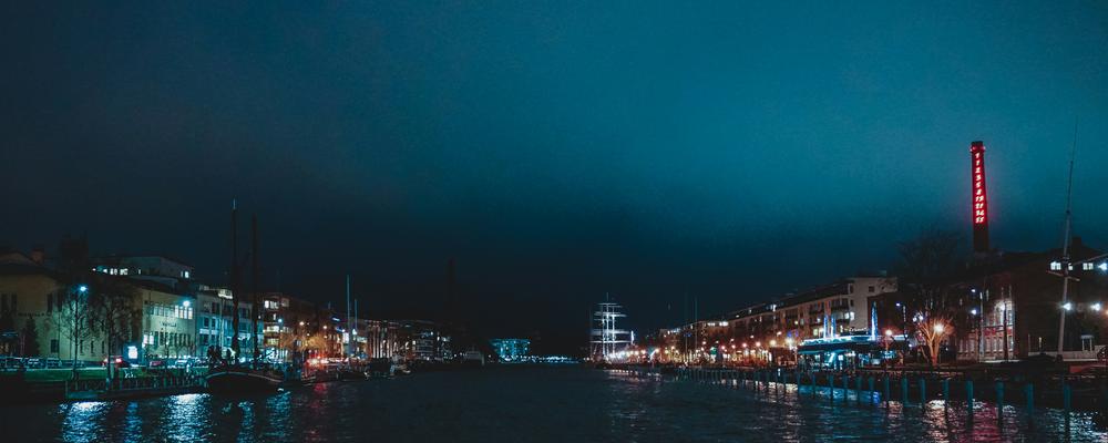 Turku harbour by night with waterfront, buildings, boats under a highlightened sky