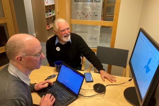 Two men looking at a computer screen showing the Irish SDG toolbox.